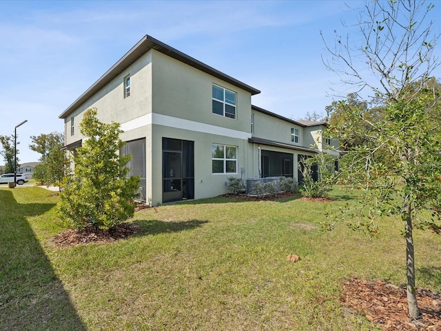 rear view of house featuring stucco siding and a yard