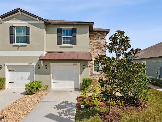 view of front of property with metal roof, an attached garage, stone siding, concrete driveway, and a standing seam roof