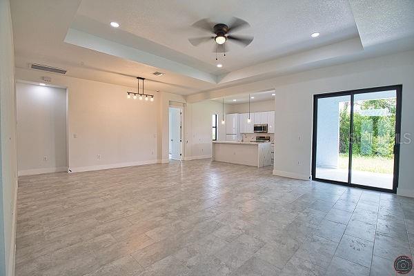9 Tee View Rd, Rotonda West, FL 33947 - unfurnished living room with a tray ceiling, a ceiling fan, recessed lighting, and a textured ceiling