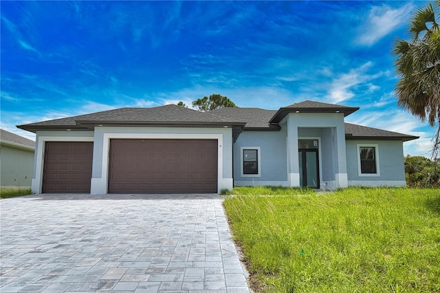 9 Tee View Rd, Rotonda West, FL 33947 - prairie-style house with an attached garage, stucco siding, decorative driveway, a front yard, and a shingled roof