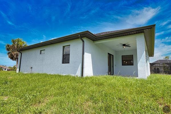 9 Tee View Rd, Rotonda West, FL 33947 - view of side of home with stucco siding, a ceiling fan, and a lawn