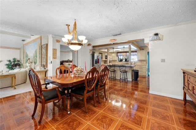 dining space with a chandelier, crown molding, a textured ceiling, and baseboards