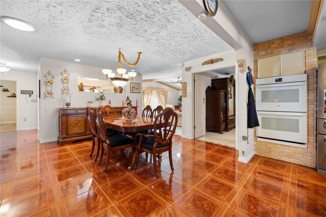 tiled dining area featuring a textured ceiling, baseboards, and ceiling fan with notable chandelier