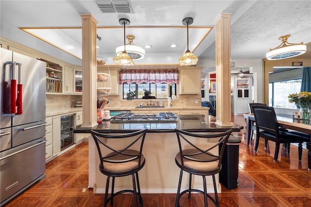 kitchen featuring stainless steel appliances, beverage cooler, visible vents, and decorative columns