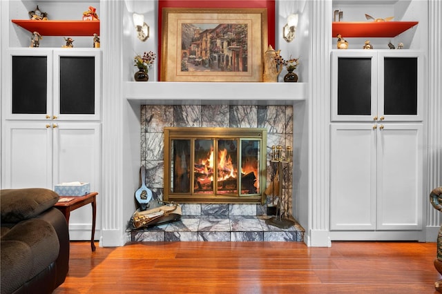 interior space with built in shelves, a fireplace, and wood finished floors