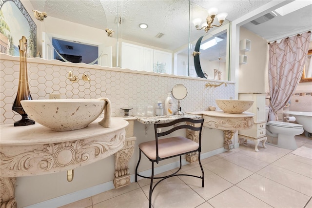 bathroom with visible vents, a sink, tile patterned flooring, a textured ceiling, and backsplash