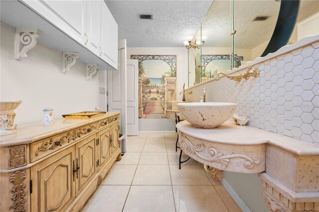 kitchen with light tile patterned flooring, a sink, visible vents, and a textured ceiling