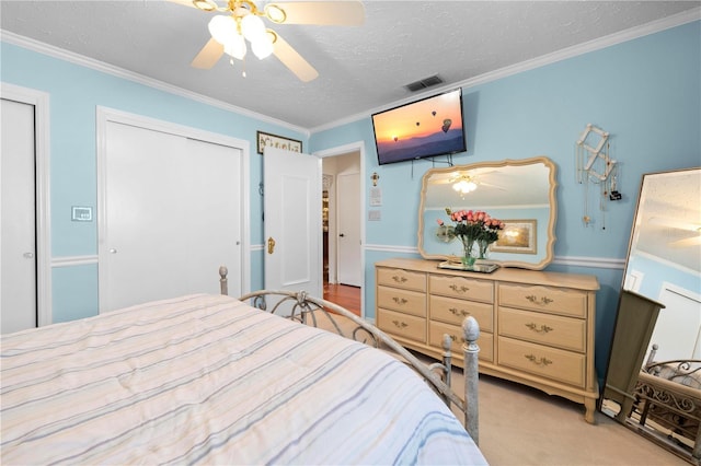 bedroom featuring light carpet, visible vents, ceiling fan, ornamental molding, and a textured ceiling