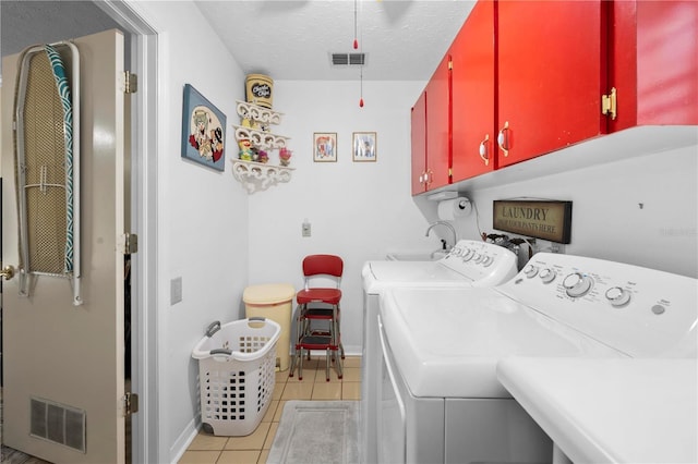 washroom with washing machine and clothes dryer, light tile patterned floors, visible vents, cabinet space, and a textured ceiling