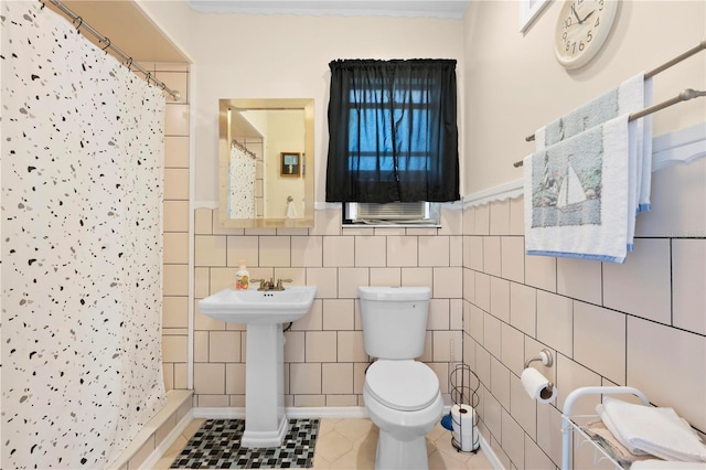 bathroom with curtained shower, tile patterned flooring, toilet, and tile walls