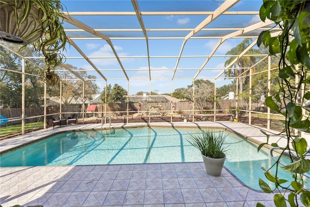 view of swimming pool featuring a lanai, a fenced backyard, and a patio