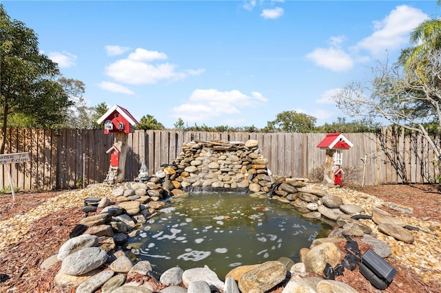 exterior space featuring a fenced backyard and a garden pond