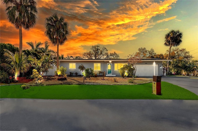 mid-century inspired home featuring an attached garage, a lawn, driveway, and stucco siding