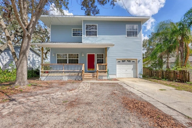 view of front facade with covered porch, fence, concrete driveway, and an attached garage