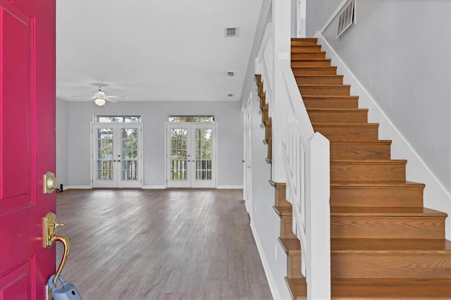 foyer with wood finished floors, visible vents, baseboards, french doors, and stairway