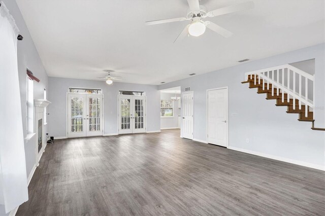 unfurnished living room featuring baseboards, visible vents, wood finished floors, stairs, and french doors