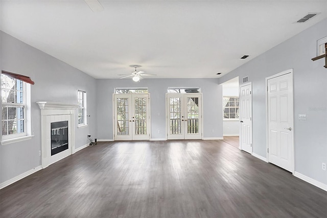 unfurnished living room featuring dark wood-style floors, french doors, visible vents, a tiled fireplace, and baseboards