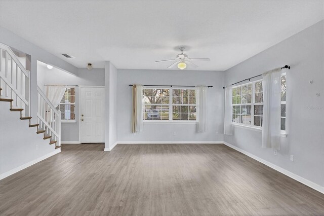 unfurnished living room featuring stairs, baseboards, and wood finished floors