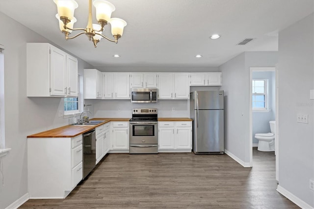 kitchen with visible vents, appliances with stainless steel finishes, white cabinets, a sink, and baseboards