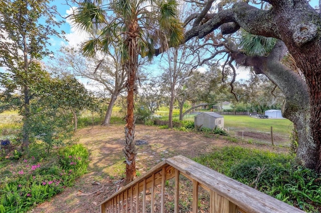 view of yard featuring an outdoor structure, fence, and a shed