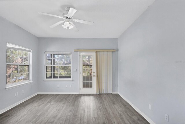 empty room featuring baseboards, wood finished floors, a ceiling fan, and a healthy amount of sunlight