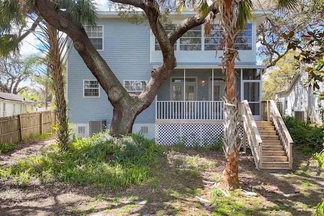 back of property with a sunroom, stairs, fence, and central AC