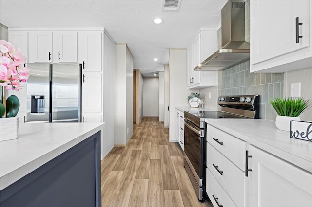 kitchen featuring appliances with stainless steel finishes, light countertops, visible vents, and wall chimney exhaust hood