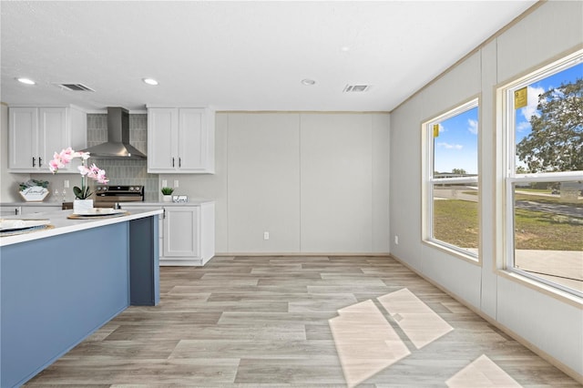 kitchen with light countertops, visible vents, wall chimney exhaust hood, and stainless steel electric stove