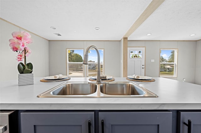 kitchen featuring gray cabinets, light countertops, a sink, and a textured ceiling