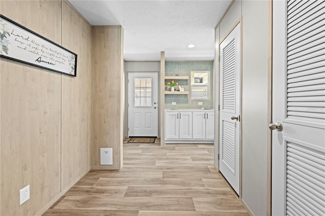 corridor with a textured ceiling and light wood-style flooring