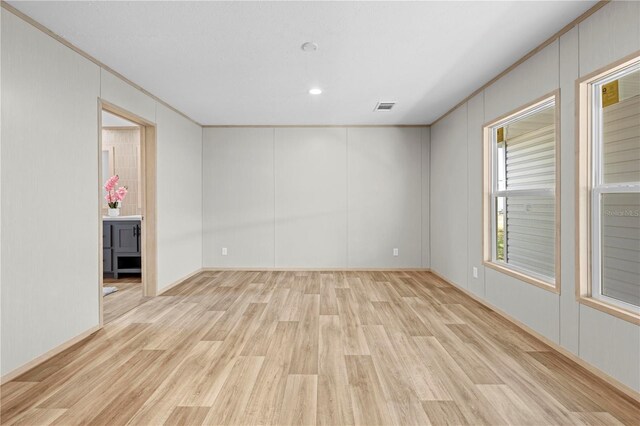 unfurnished room featuring light wood finished floors, visible vents, and crown molding