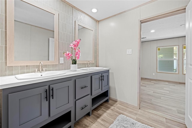 full bathroom with recessed lighting, double vanity, a sink, and wood finished floors