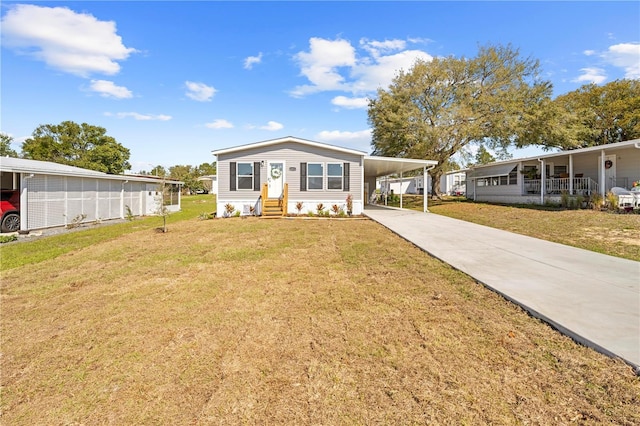 manufactured / mobile home with entry steps, driveway, a front lawn, and an attached carport