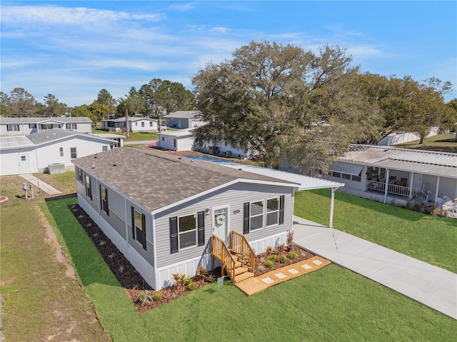 view of front facade featuring a shingled roof, a residential view, and a front lawn