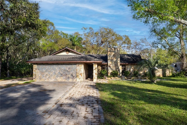 view of front facade featuring a chimney, a front yard, a garage, stone siding, and driveway