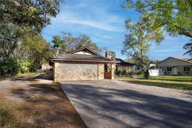 view of property exterior featuring stone siding, driveway, a chimney, and an attached garage