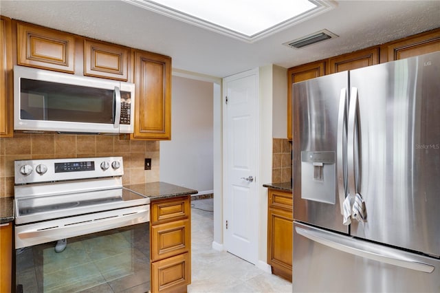 kitchen featuring stainless steel appliances, tasteful backsplash, visible vents, and brown cabinets