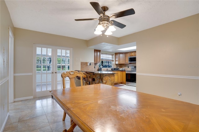 dining space with light tile patterned floors, a textured ceiling, a ceiling fan, baseboards, and french doors