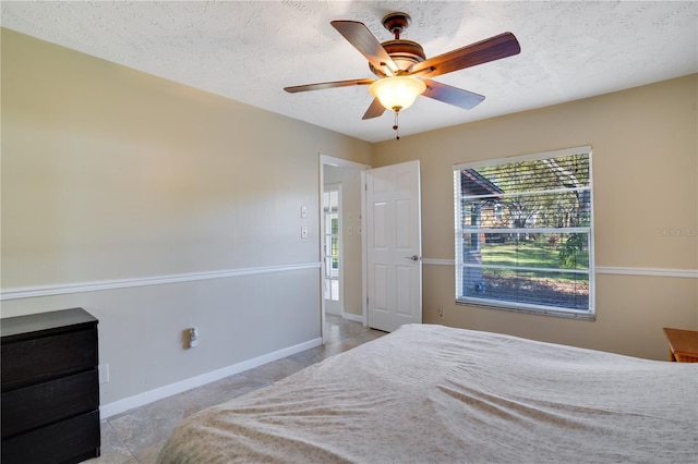 bedroom with a ceiling fan, baseboards, and a textured ceiling