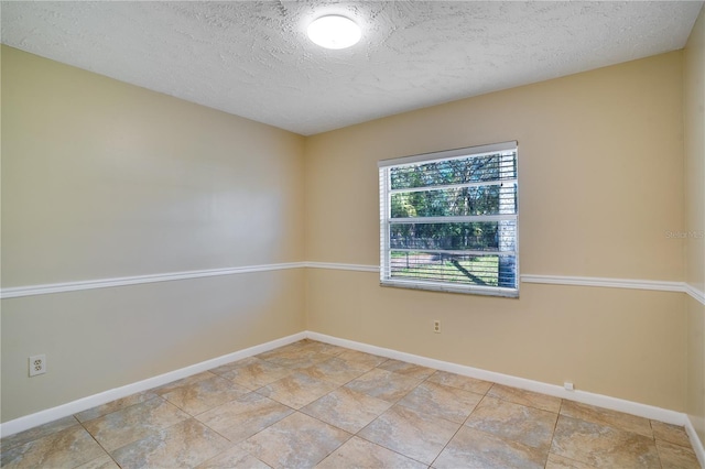 empty room featuring a textured ceiling and baseboards