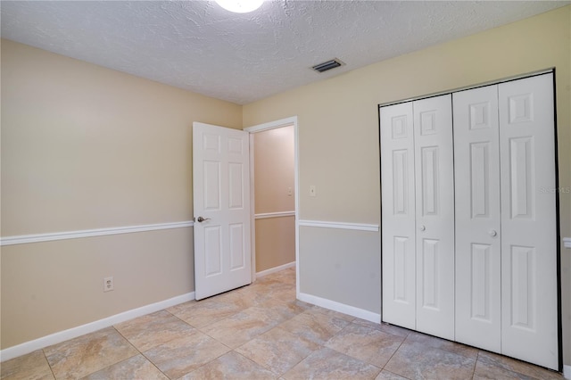 unfurnished bedroom featuring baseboards, a textured ceiling, visible vents, and a closet