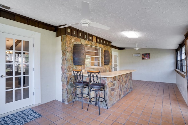 kitchen featuring ceiling fan, a textured ceiling, visible vents, and tile patterned flooring