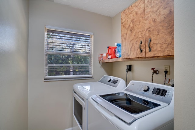 clothes washing area with cabinet space, a textured ceiling, and independent washer and dryer