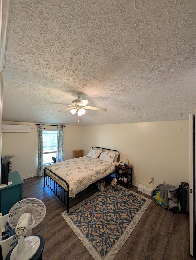 bedroom featuring a textured ceiling, baseboards, wood finished floors, and an AC wall unit