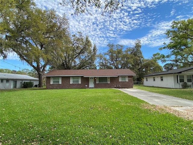 single story home featuring brick siding, concrete driveway, and a front yard