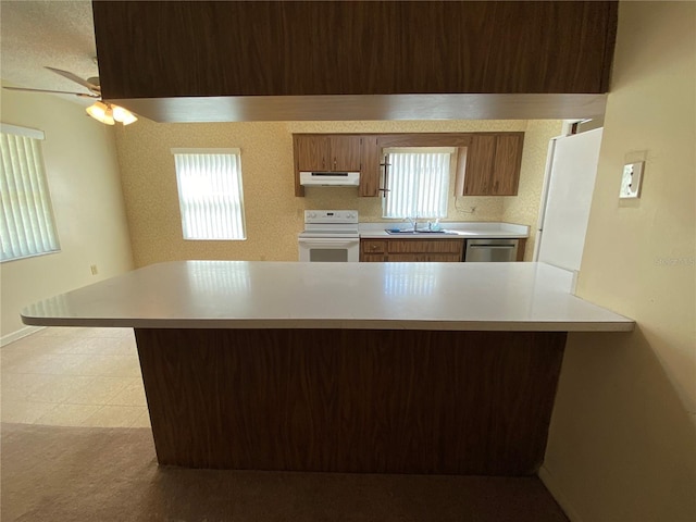 kitchen with a sink, stainless steel dishwasher, white electric range oven, a peninsula, and light countertops