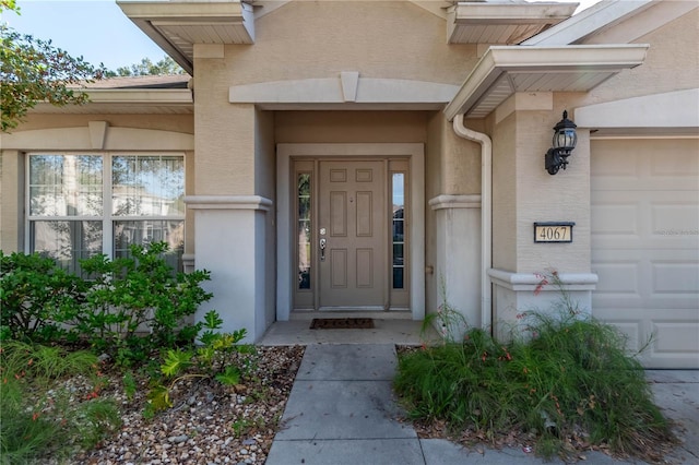 doorway to property with an attached garage and stucco siding