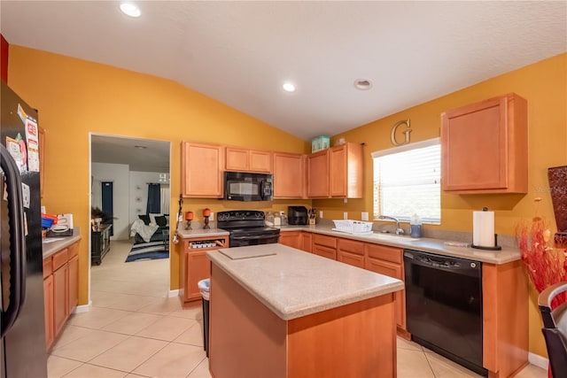 kitchen with light brown cabinets, vaulted ceiling, light countertops, a center island, and black appliances