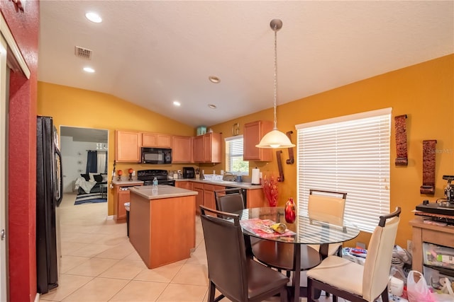 kitchen with light tile patterned flooring, a kitchen island, vaulted ceiling, light countertops, and black appliances