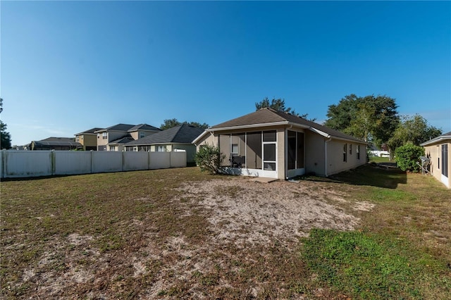 back of property with a sunroom, fence, and a lawn